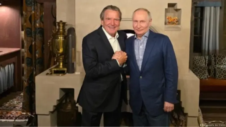 Володимир Путін і Герхард Шредер біля «традиційної російської печі» із самоваром і валянками